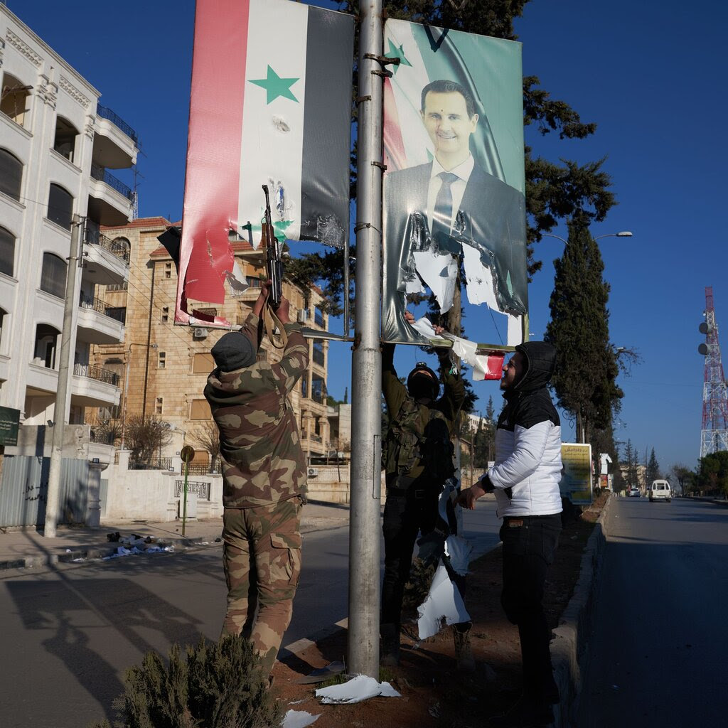 Syrian opposition fighters tear up a portrait of President Bashar al-Assad.