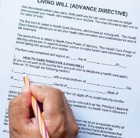 A hand filling out a living will (advance directive) document