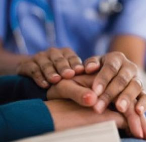 A nurse's hands laying on top of another pair of hands in a gesture of comfort