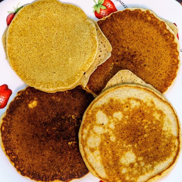 Aerial view of four pancakes on a white plate with strawberry illustrations