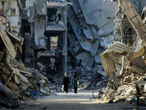 Jeudi, des femmes palestiniennes passent devant des bâtiments détruits à Khan Yunis.