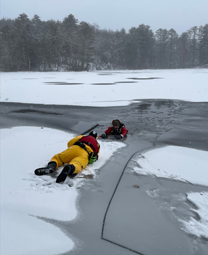 Ranger lays on ice as they help the other out of the water