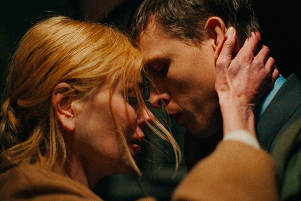 A woman and man embrace with foreheads touching 