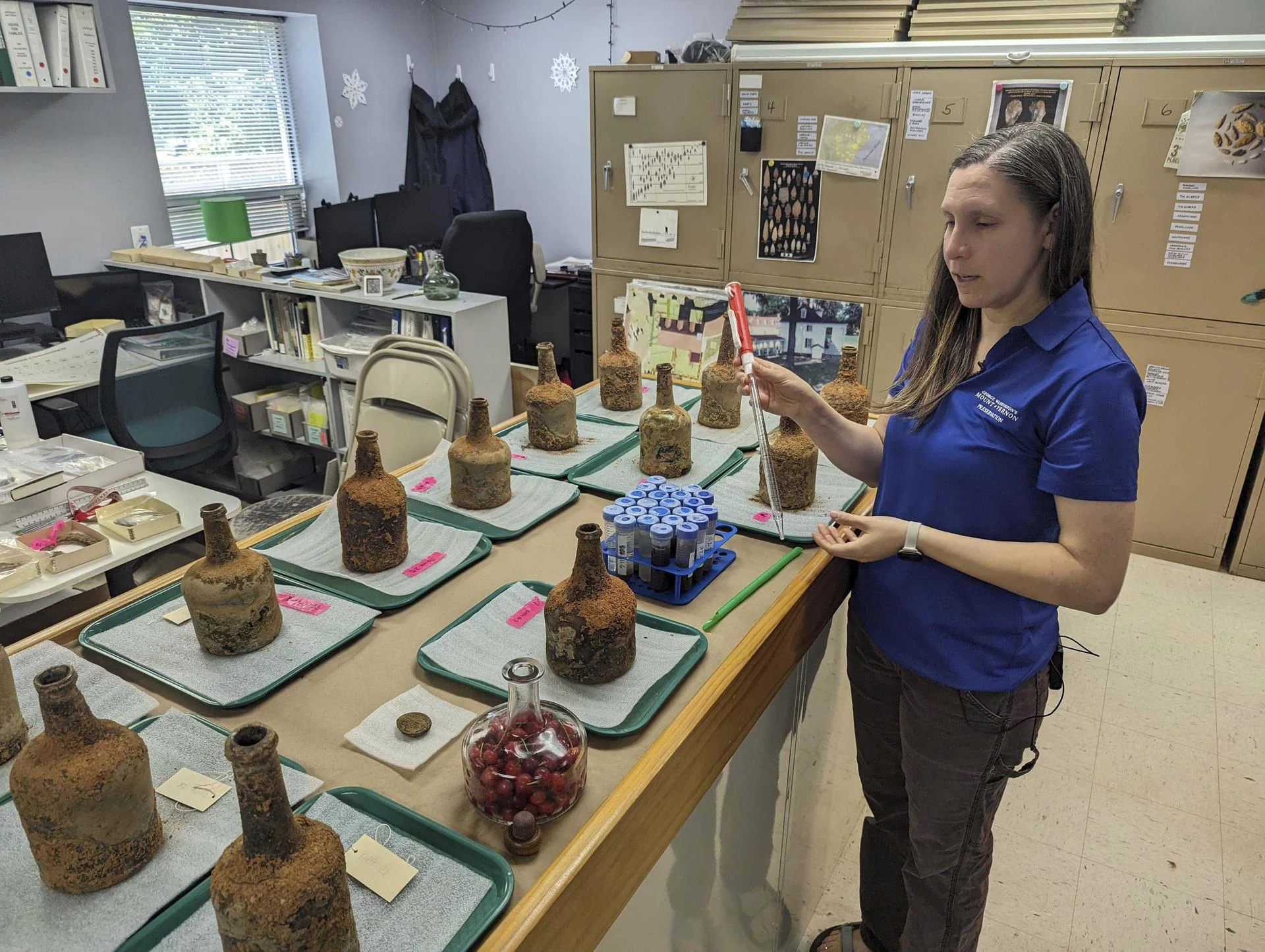 A curator stands next to 18-century bottles.