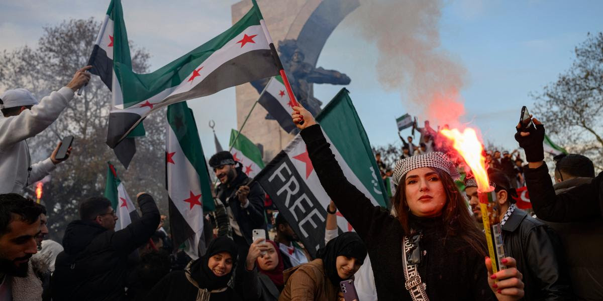 People holds a Syrian opposition flag and a flare as members of the Syrian community and supporters gather to celebrate the fall of Syrian president Bashar al-Assad in the face of an offensive by Islamist-led rebels, in Istanbul on December 8, 2024. - Islamist-led rebels toppled Syria's longtime ruler Bashar al-Assad in a lightning offensive that a UN envoy called "a watershed moment" for the nation marred by civil war. (Photo by Yasin AKGUL / AFP)