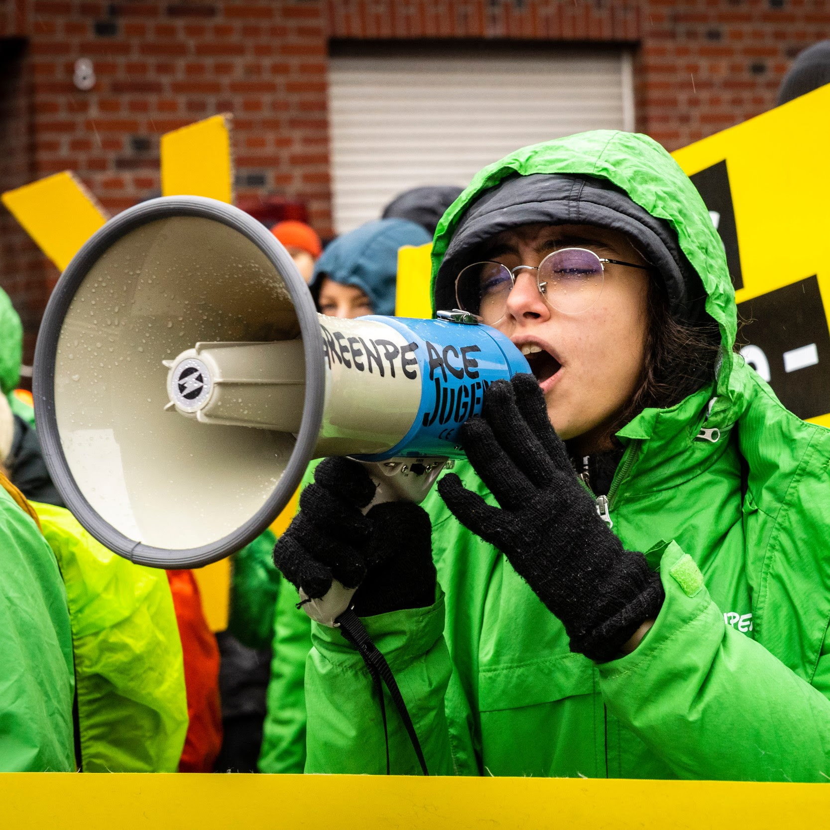 Militante de Greenpeace qui parle dans un mégaphone.