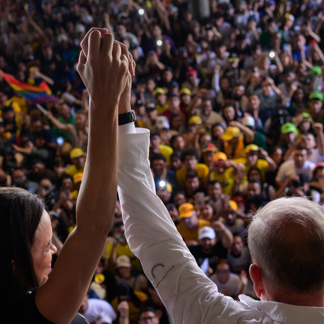 The Venezuelan opposition leader María Corina Machado and the presidential candidate Edmundo González raise their held hands in front of a crowd.