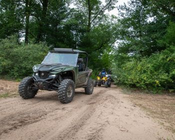 An ORV races down a forest road.