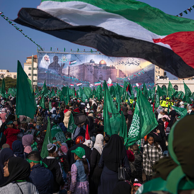 A crowd with green banners, a Palestinian flag streaming above them.