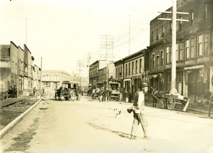 Vancouver’s Chinatown in the late 19th century A photograph of Vancouver’s Chinatown in the late 19th century, with horses and carts in the street and a man crossing a road