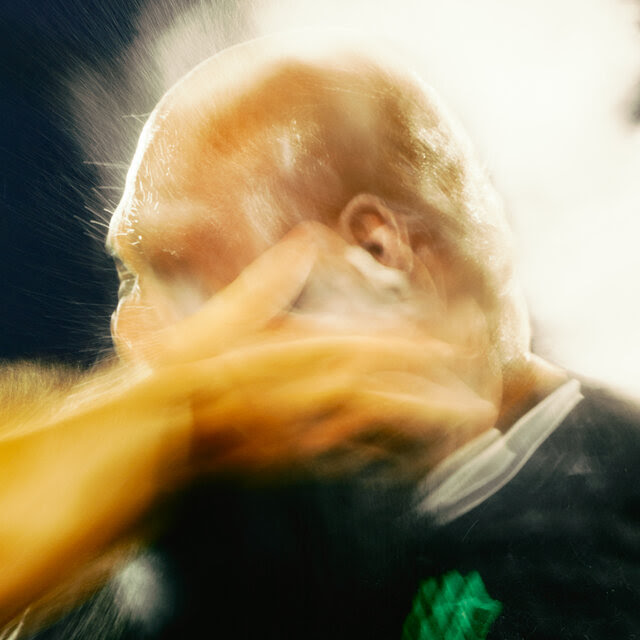 A blurry image of a bald man being struck in the face.