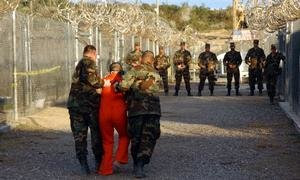 La policía militar del ejército estadounidense escolta a un detenido a su celda en el Campamento X-Ray en la Base Naval de Guantánamo, Cuba, en 2002.