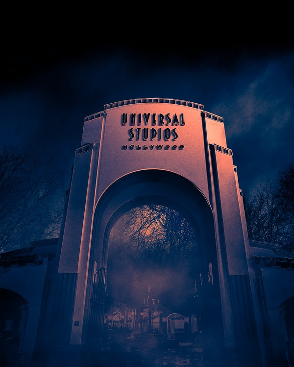 The Universal Studios Hollywood front entrance arch during Halloween Horror Nights on a dark, foggy night.