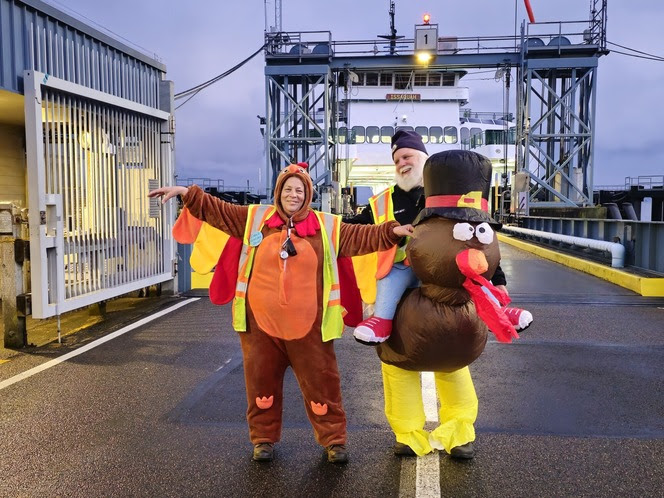 Two people in fun turkey costumes on the dock at Vashon terminal standing in front of the ferry Issaquah