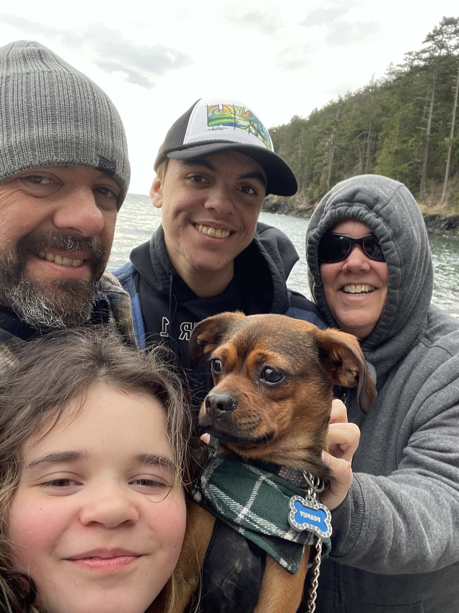 A family and their dog with water and trees in the background