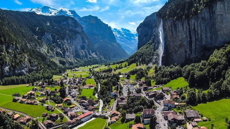 houses on green grass field near mountain under blue sky during daytime