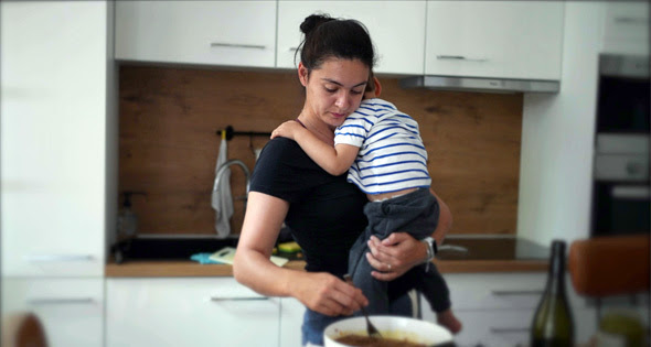 Woman holding child cooking stew