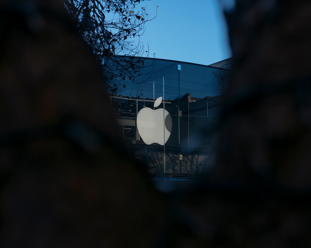 A white Apple logo displayed on a dark building.