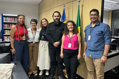 Fotografia de um grupo de 4 mulheres e 2 homens em pé, de frente para a câmera, em uma sala da PRPI, sendo um dos homens o procurador regional dos Direitos do Cidadão, Patrício Noé da Fonseca, e as demais pessoas representantes do PPDDH