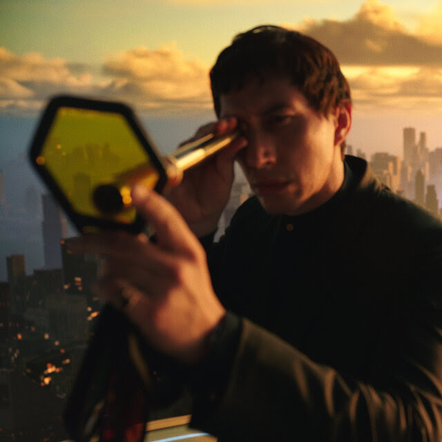 Adam Driver and Nathalie Emmanuel appear to be standing on a high perch with a vast skyline behind them, Driver holding a telescope to one eye. 