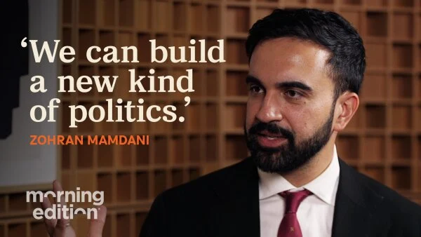 Zohran Mamdani is seen from the shoulders up on the right side of the screen in a suit with a red tie. On the left side, top corner of the image are the words ‘We can build a new kind of politics.’ -Zohran Mamdani. 