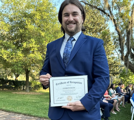 Andrew Heise standing with his award certificate
