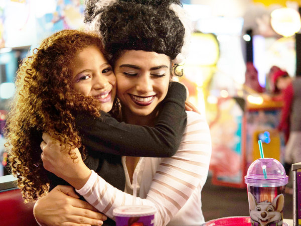 Mother and daughter hugging at Chuck E. Cheese table