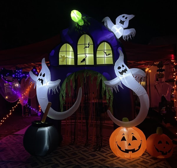 nighttime view of campsite decorations including inflated ghosts, pumpkins, a blow-up window with bats, pumpkin lights and more