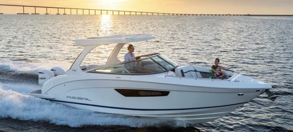 white speedboat with woman at bow and sunset background