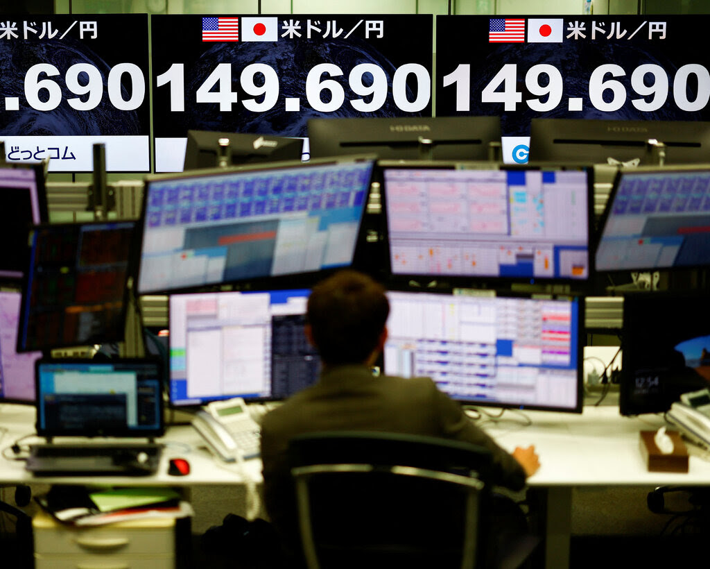 A trader sitting in front of monitors showing exchange rates. 