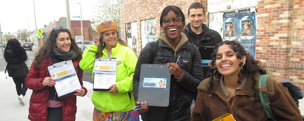 a crew of street ambassadors wearing
chilly-weather clothing, led by Makayla Comas, a black woman with her
hair pulled back and wearing hoop earrings. They are all smiling at
the camera and some hold clipboards displaying the Street Ambassador
forms