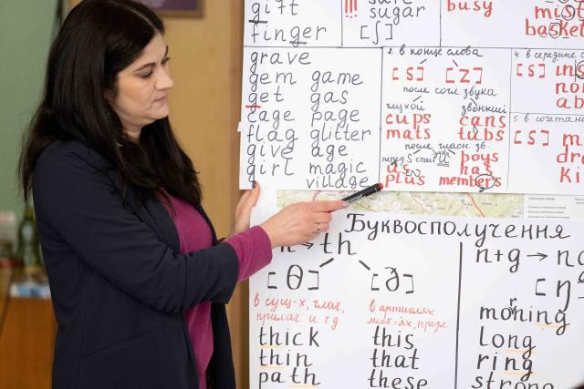 Teacher from Ukraine teaching from a paper on a partical boards