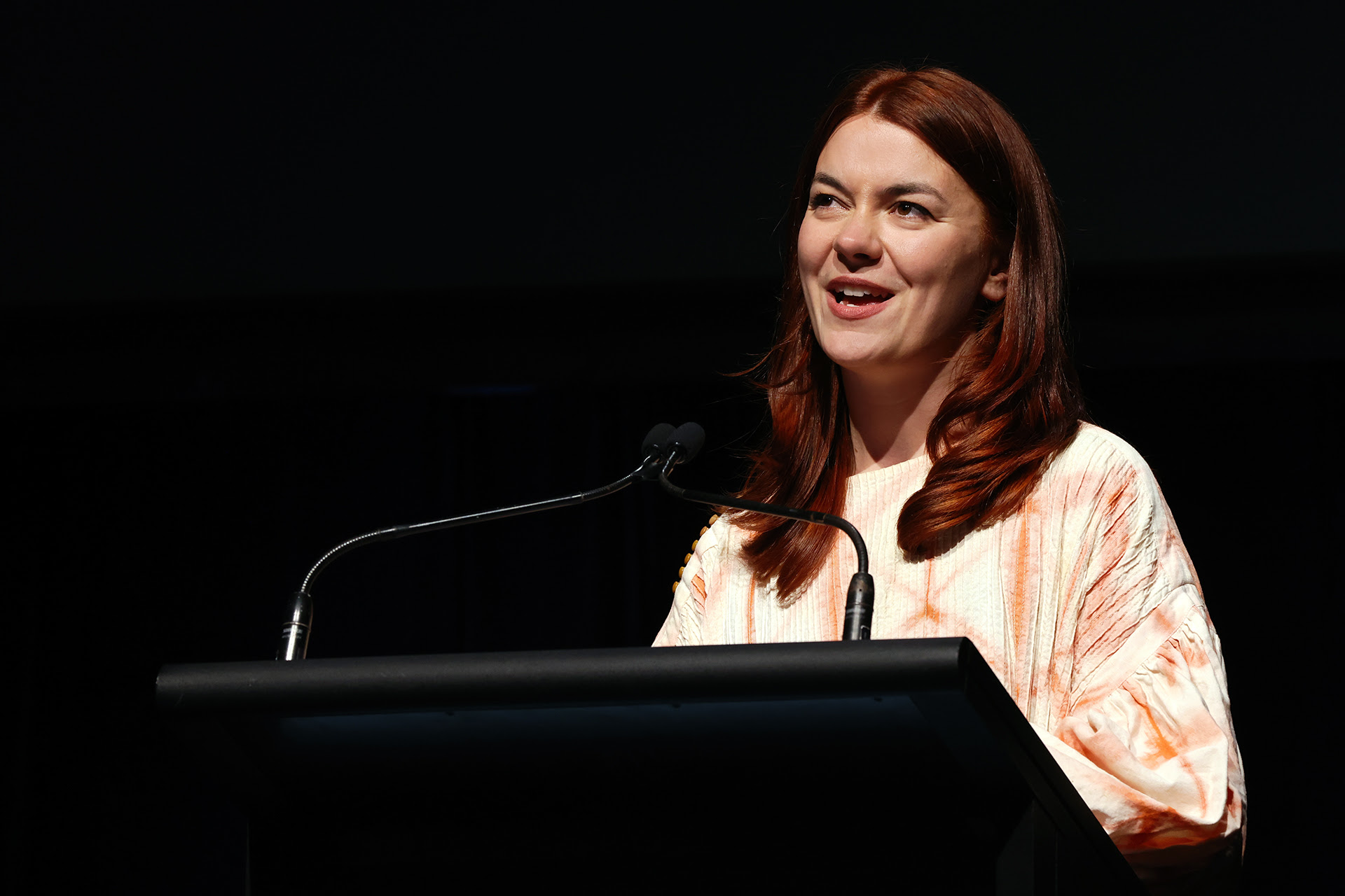 A person at a lectern reading poetry