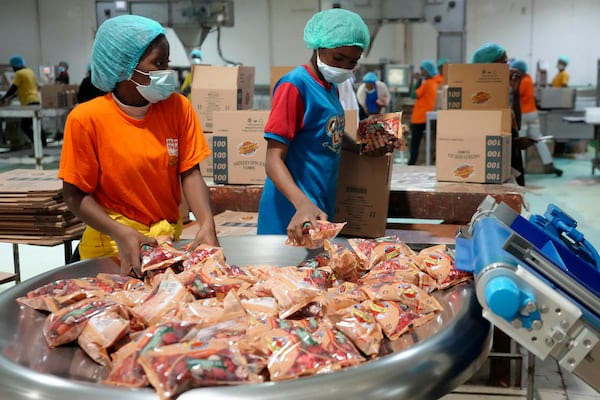 Workers collect bouillon cube packages at the Sweet Nutrition factory in Otta, Nigeria. The foundation has said adding nutrients to bouillon could save lives. AP