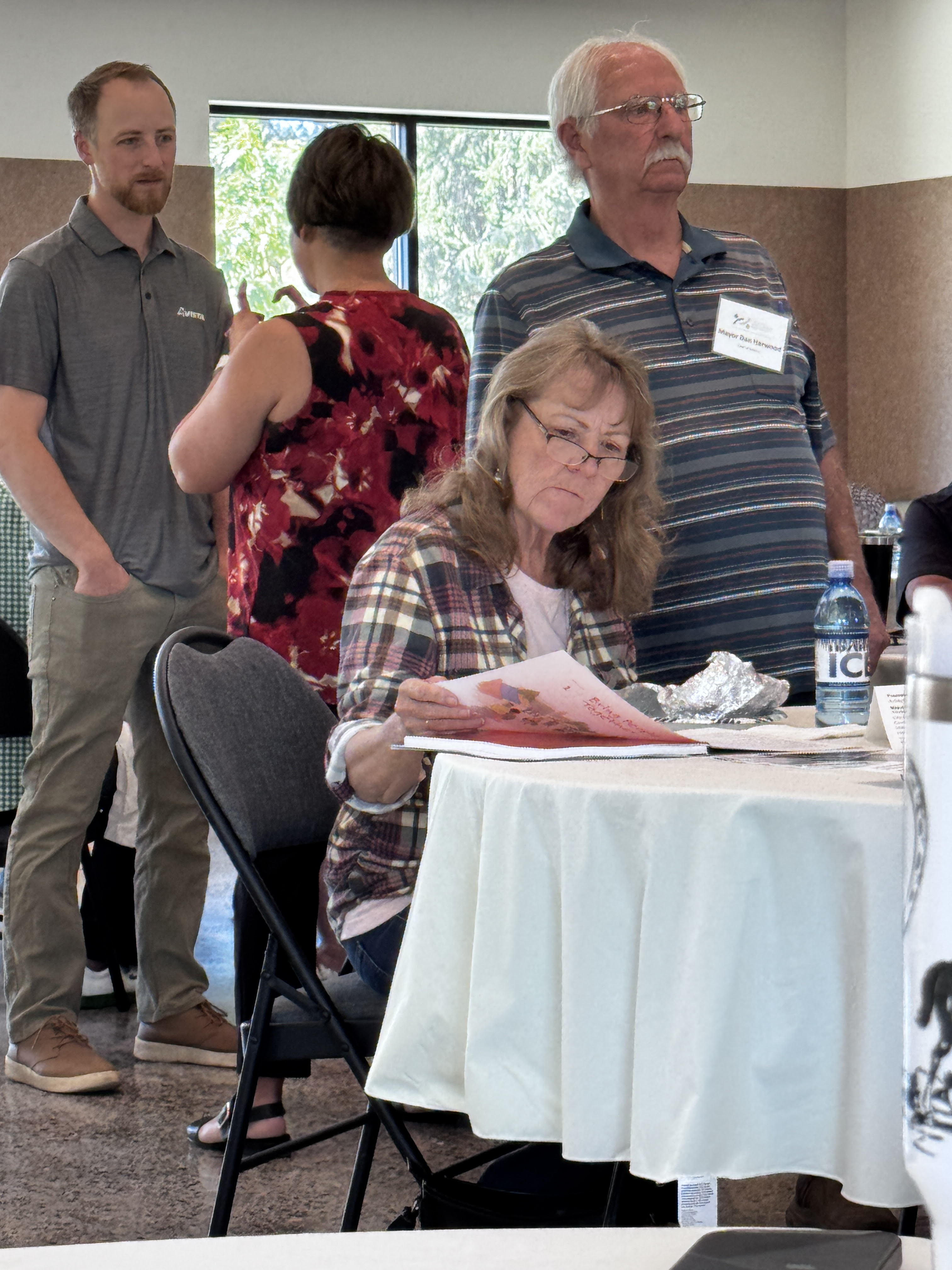 A woman reading a book on the table as her husband the mayor of Malden WA looks on