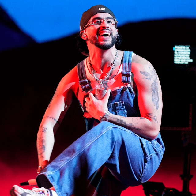 A bearded man in overalls, a backward baseball cap and wire-rimmed glasses smiles as he dances onstage.