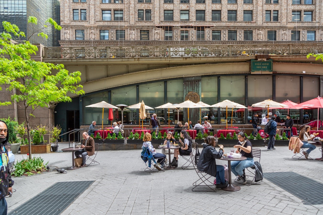 Photo of an outdoor space with people sitting and eating at tables