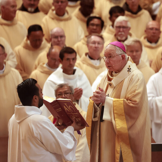 The Archbishop José H. Gomez stands with hands clasped, looking out.