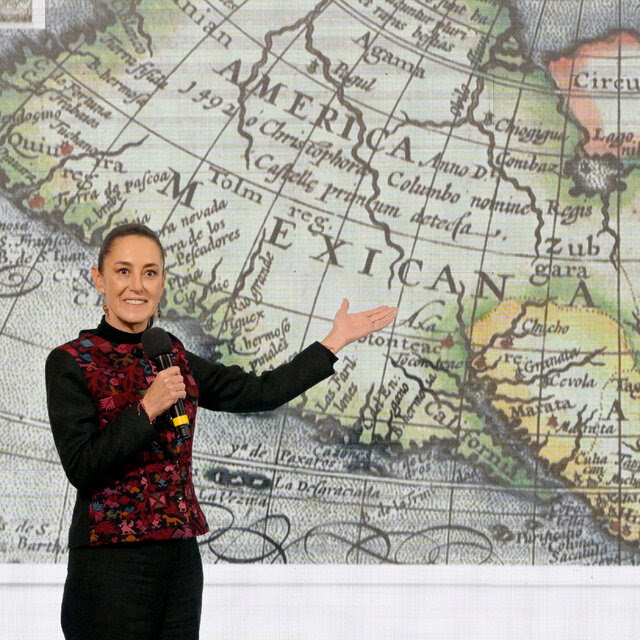 President Claudia Sheinbaum of Mexico standing in front of a map.