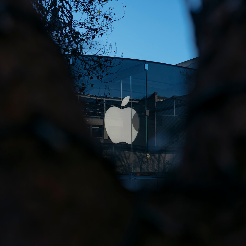 A white Apple logo is displayed on a dark building.
