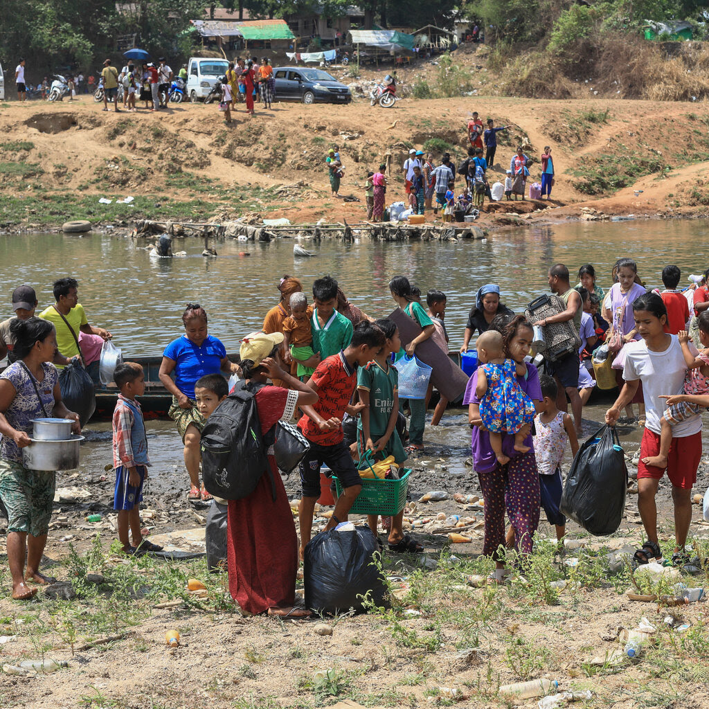 Two groups of people congregate on the banks of both sides of a river.