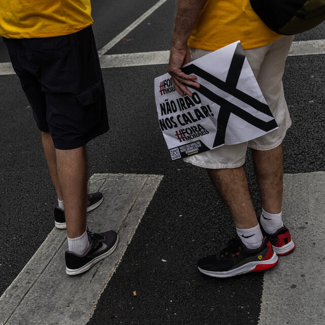 A person holds a sign on a street.