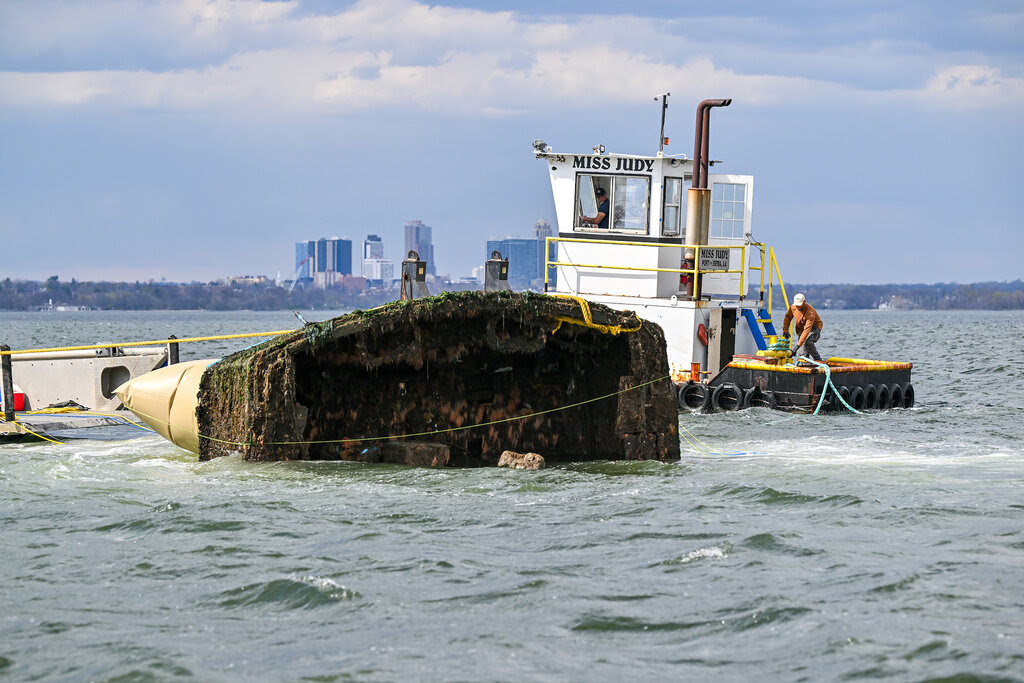 An abandoned boat is pulled away with ropes.