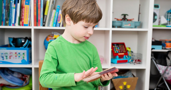 Pre-school aged child with disabilities holding sensory device in classroom