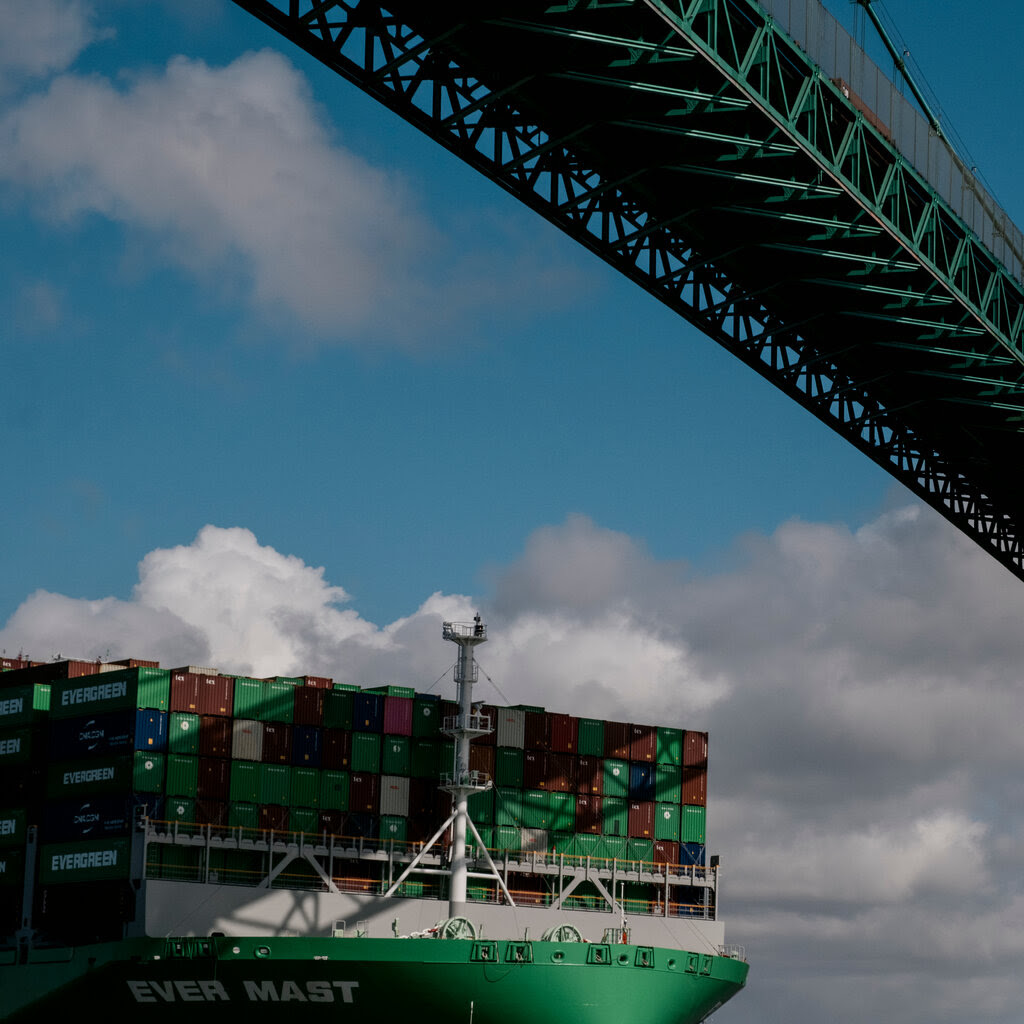 A container ship passing underneath a bridge.