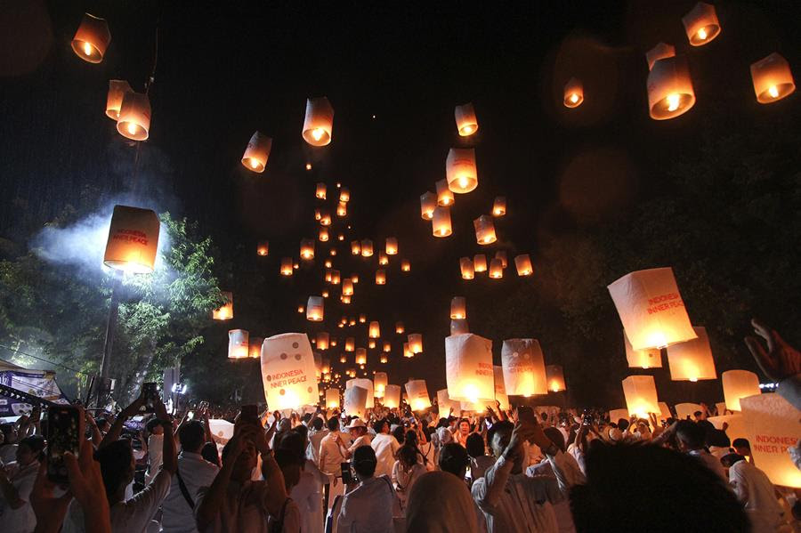 A wide view of a crowd of people releasing paper lanterns into the sky.