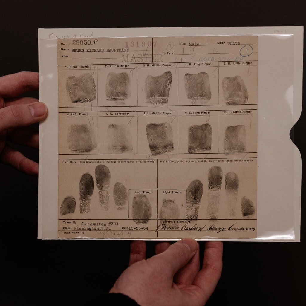 Hands holding up a page with fingerprints.