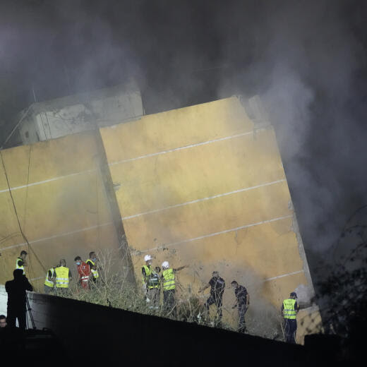 Rescuers gather as smoke rises from a collapsed building at the site of an Israeli airstrike in Beirut's southern suburbs, Friday, Sept. 27, 2024. (AP Photo/Hassan Ammar)