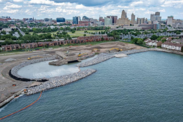 Aerial view of a construction site for habitat restoration with heavy machinery near a water body Buffalo, New York in the background