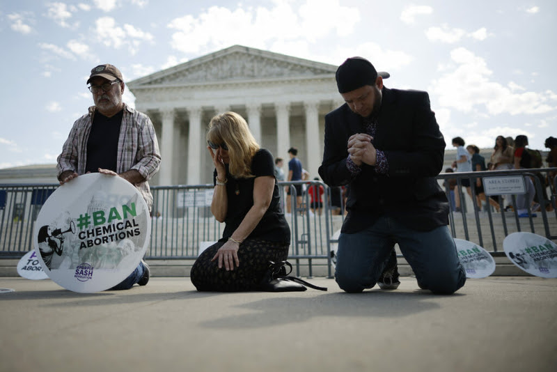 Rev. Pat Mahoney, Peggy Nienaber of Faith and Liberty and Mark Lee Dickson of Right to Life East Texas pray in front of the U.S. Supreme Court on April 21, 2023. Some abortion-rights opponents say the Comstock Act of 1873 can ban abortion pills, which experts say is divorced from the law’s purpose. (Chip Somodevilla/Getty Images)